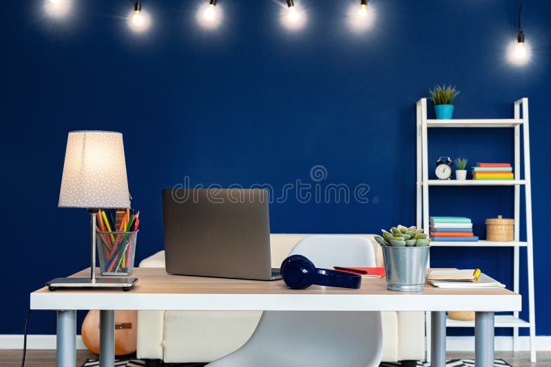 Working table with laptop against blue wall in modern flat