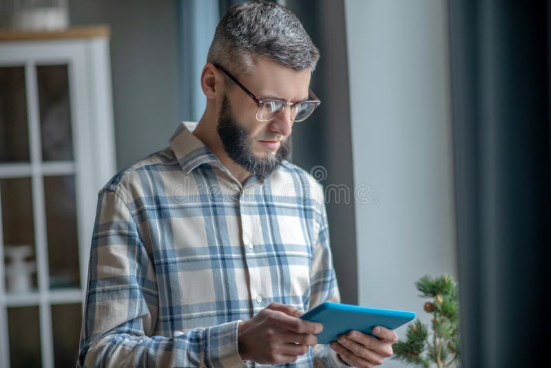 Young man in glasses with a tablet in his hands.