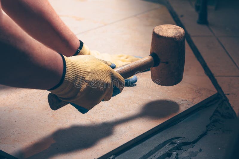 The working tiler knocks on the tile with a Tile Mallet stock images