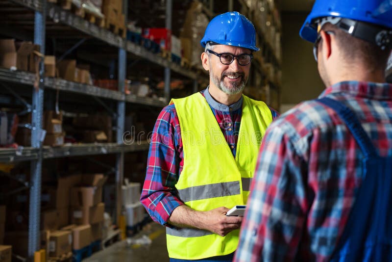 Working in warehouse, managers and workers checking inventory. stock image