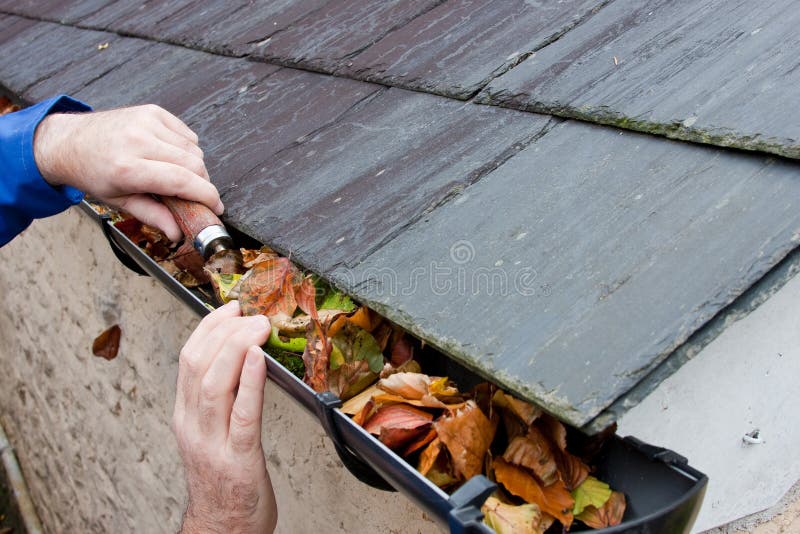 Workman Clearing Autumn Leaves from Gutter royalty free stock image Workman Clearing Autumn Leaves from Gutter royalty free stock image