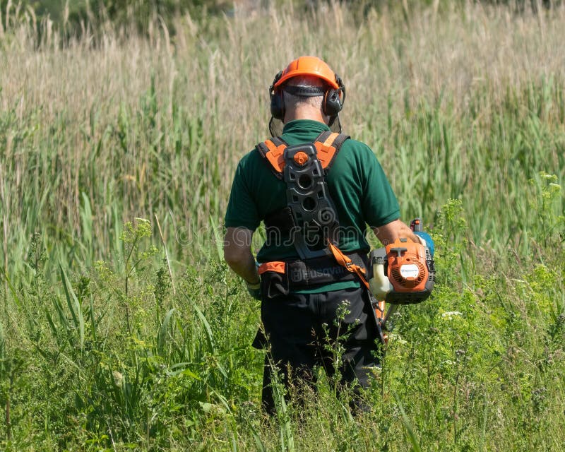 Workman clearing long grass and weeds stock photos