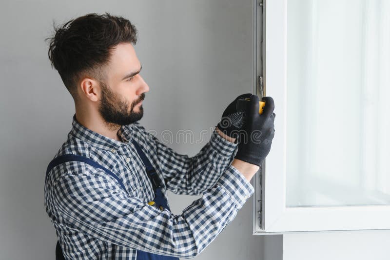 Workman in Overalls Installing or Adjusting Plastic Windows in the