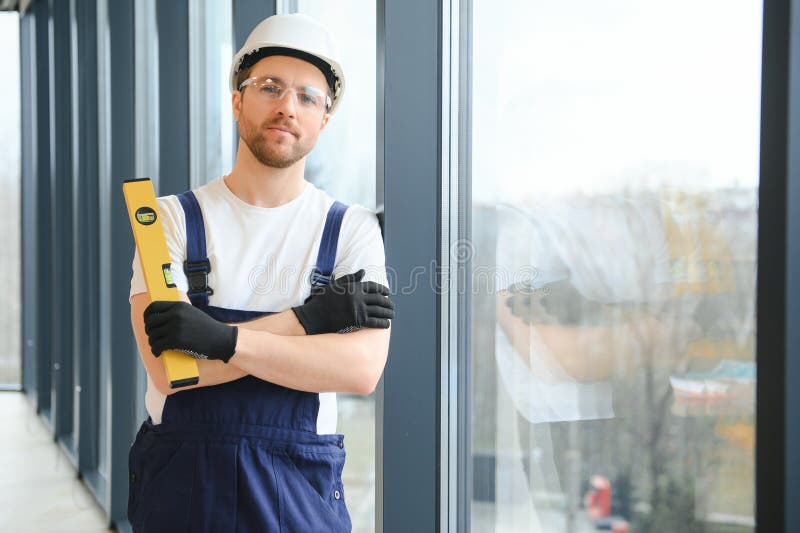 Workman in Overalls Installing or Adjusting Plastic Windows in the