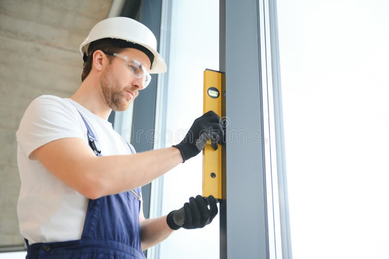 Workman in Overalls Installing or Adjusting Plastic Windows in the