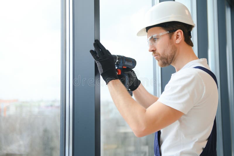 Workman in Overalls Installing or Adjusting Plastic Windows in the