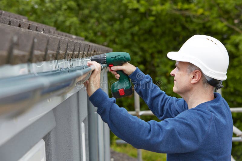 Workman Replacing Guttering On Exterior Of House