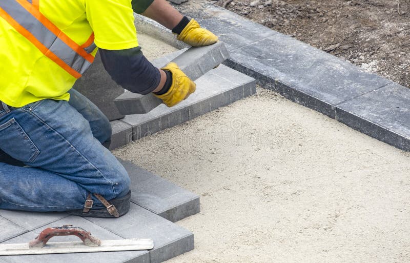 Workman in Yellow Safety Jacket Laying Patio Paver Stones 3 stock image Workman in Yellow Safety Jacket Laying Patio Paver Stones 3 stock image
