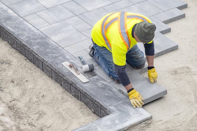 Workman in Yellow Safety Jacket Laying Patio Paver Stones 2