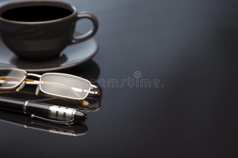 Workong environment black table or place with cup of coffee glasses pen
