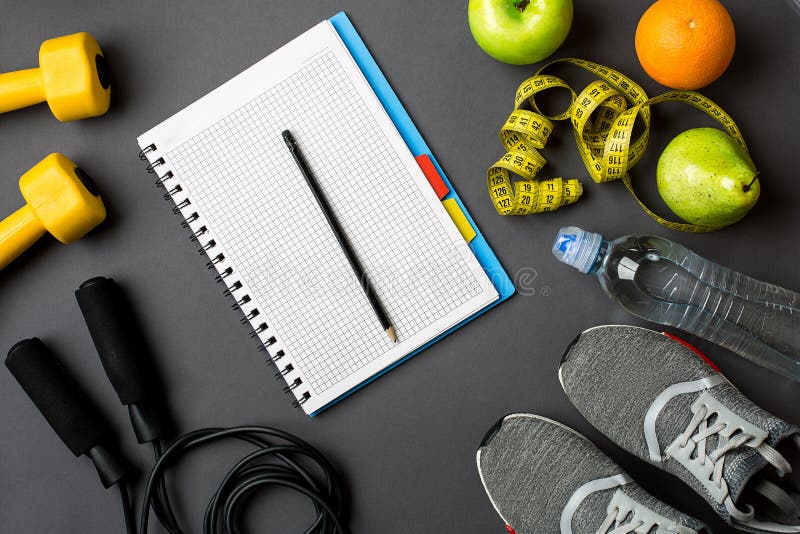 Workout plan with fitness food and sport equipment on gray background, top view. Copy space. Still life flat lay. Workout plan with fitness food and sport equipment on gray background, top view. Copy space. Still life flat lay