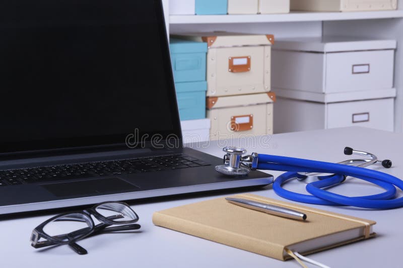 Workplace of doctor with laptop, stethoscope, RX prescription, glasses and notebook on white table. Copy space.