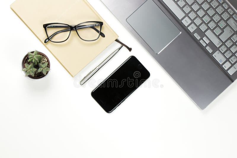 Workplace still life from above with laptop, notebook, black smartphone, small cactus, pen and glasses