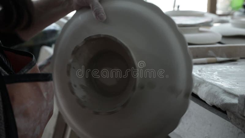 Workshop. Handmade work. A woman`s hand wipes the base of the vase with a wet sponge.