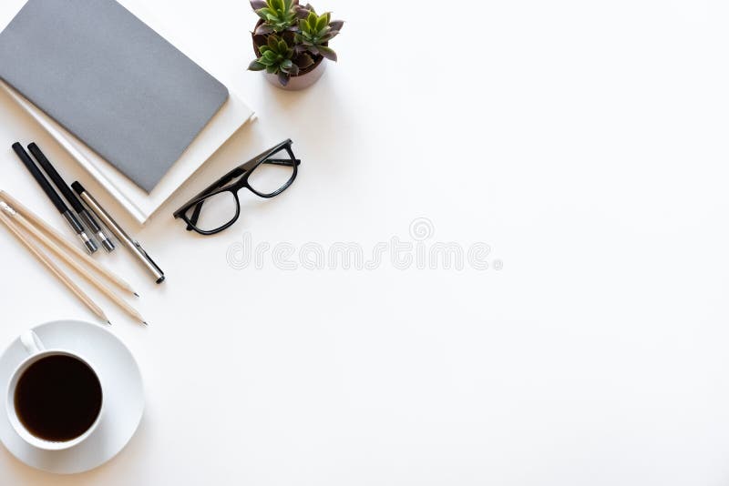 Workspace desk. Top view office desk with notebook, pencils, glasses and plant on white color background.