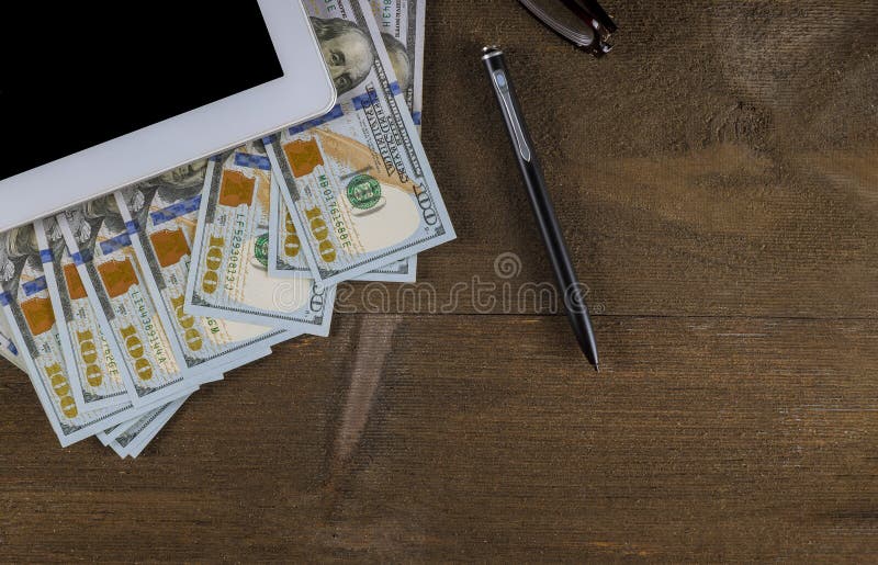 Top view workspace with money dollar bills and pen on wooden table background stock photo Top view workspace with money dollar bills and pen on wooden table background stock photo