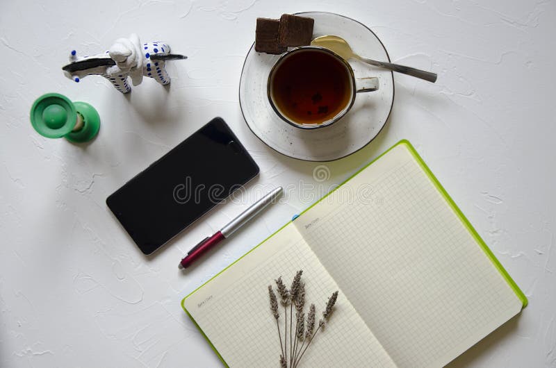 Workspace with notepad, cup of tea on a white background. Flat lay, top view office desk writing desk. Workplace freelancer. royalty free stock photography Workspace with notepad, cup of tea on a white background. Flat lay, top view office desk writing desk. Workplace freelancer. royalty free stock photography