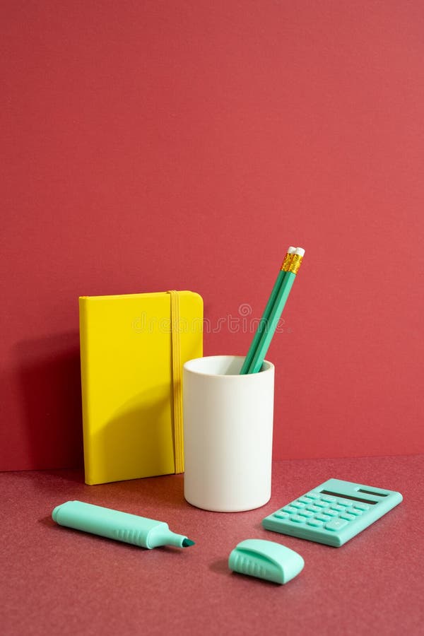 Workspace office supply stationery with note, pencil holder, highlighter calculator on red desk. red wall background. studio shot