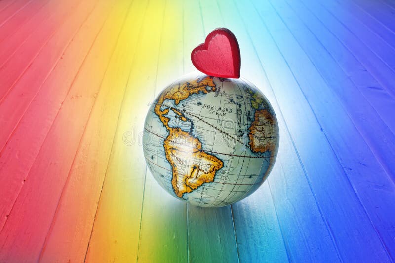 A red heart on a world globe with a rainbow background. A red heart on a world globe with a rainbow background