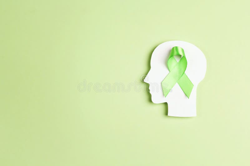 World mental health day concept. Green awareness ribbon with brain symbol on a green background