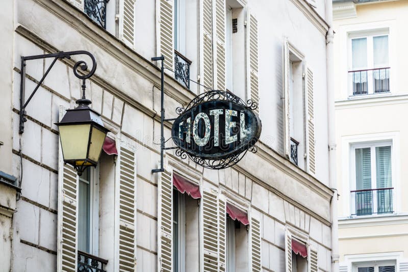 The worn period sign of an hotel and a vintage street light fixed to an old building in Paris