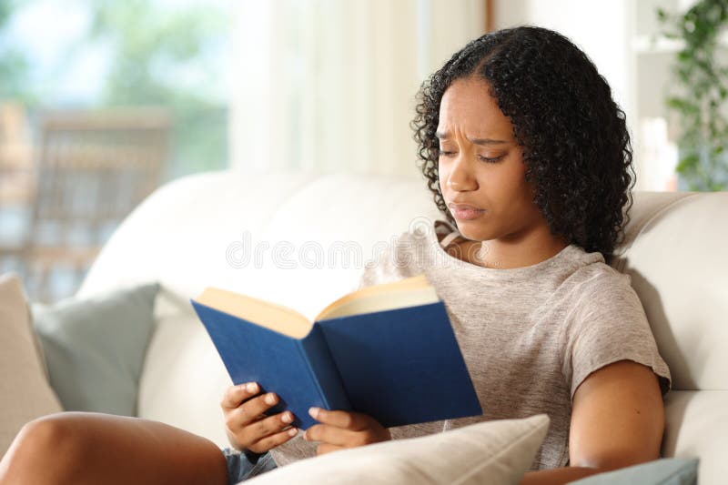 Worried black woman reading a paper book at home stock photo