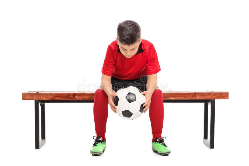 Worried boy in football shirt sitting on a bench