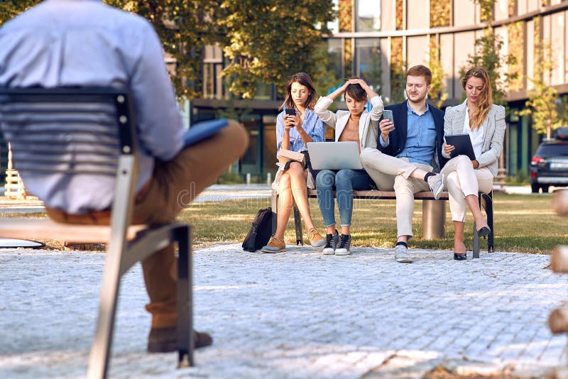 Worried businesspeople sitting outdoor in park at bench, working on laptop, cell phones, tablet. business after corona virus royalty free stock image Worried businesspeople sitting outdoor in park at bench, working on laptop, cell phones, tablet. business after corona virus royalty free stock image