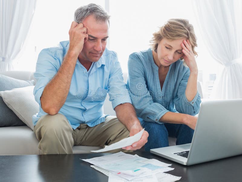 Worried couple paying their bills online with laptop stock image