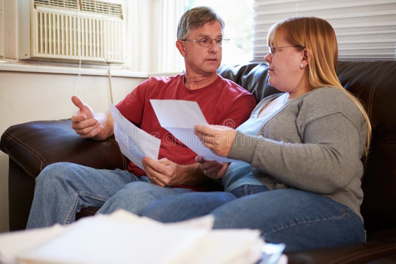 Worried Couple Sitting On Sofa Looking At Bills royalty free stock image Worried Couple Sitting On Sofa Looking At Bills royalty free stock image