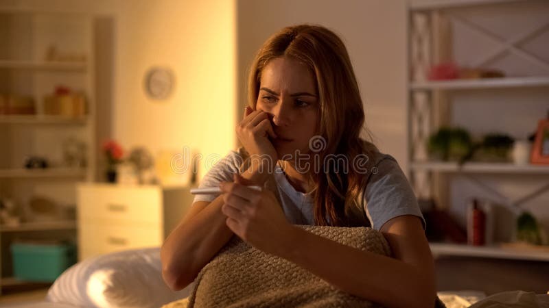 Worried female holding pregnancy test sitting on bed, infertility problems stock images Worried female holding pregnancy test sitting on bed, infertility problems stock images