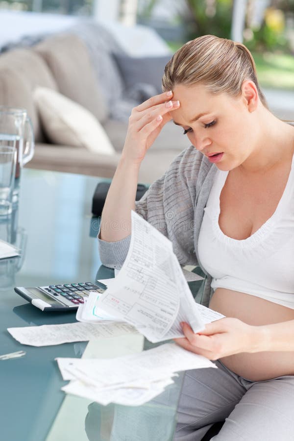 Worried pregnant woman calculating her bills stock image Worried pregnant woman calculating her bills stock image