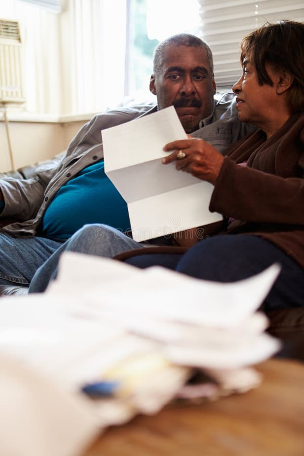 Worried Senior Couple Sitting On Sofa Looking At Bills stock photography Worried Senior Couple Sitting On Sofa Looking At Bills stock photography