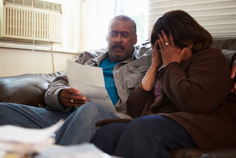 Worried Senior Couple Sitting On Sofa Looking At Bills royalty free stock photo Worried Senior Couple Sitting On Sofa Looking At Bills royalty free stock photo