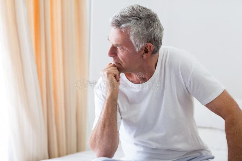 Worried senior man sitting on bed