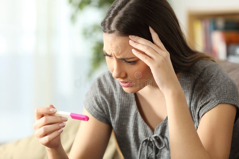 Worried woman checking a pregnancy test stock photo