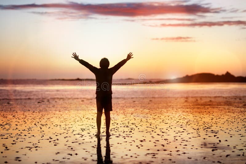 Worship and praise by the sea. Silhouette of a boy on a beach with hands raised in the sunset over the sea concept for religion, worship, prayer and praise royalty free stock photo Worship and praise by the sea. Silhouette of a boy on a beach with hands raised in the sunset over the sea concept for religion, worship, prayer and praise royalty free stock photo