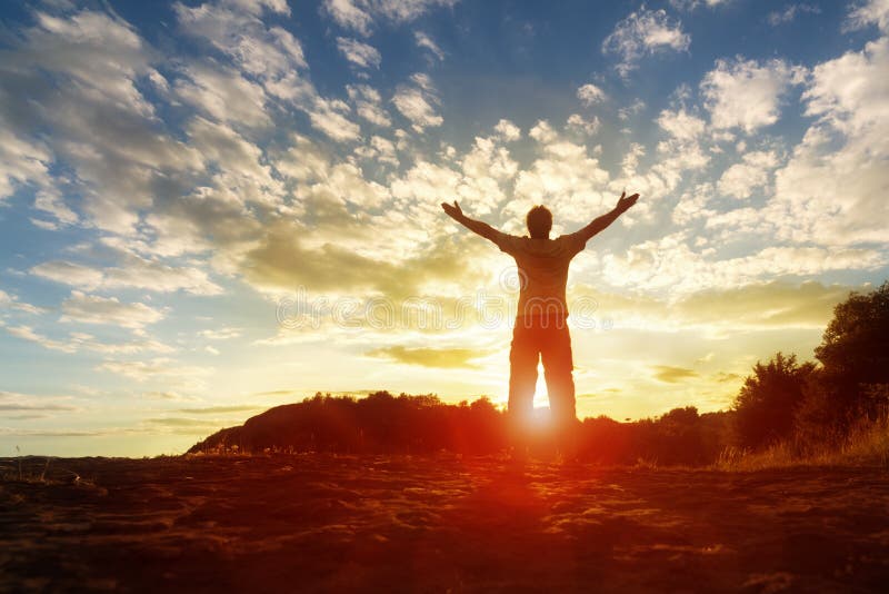 Silhouette di un uomo con le mani alzate al tramonto concetto di religione, di culto, di preghiera e di lode.