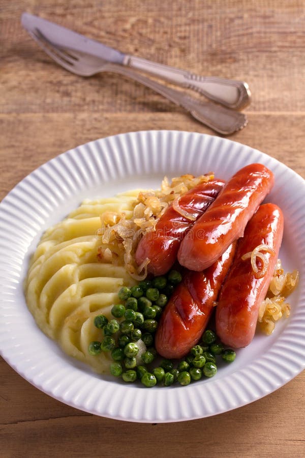 Worsten, fijngestampte aardappels, groene erwten en uijus Eigengemaakte Bangers en Brij stock afbeelding Worsten, fijngestampte aardappels, groene erwten en uijus Eigengemaakte Bangers en Brij stock afbeelding