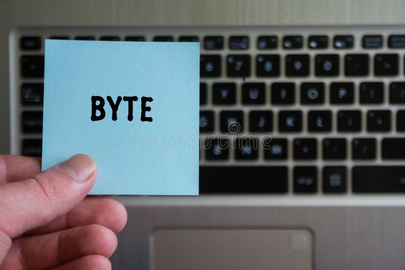 Wort BYTE auf klebrigem Anmerkungsgriff in der Hand auf Tastaturhintergrund