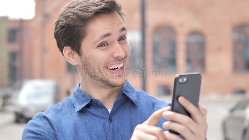 Wow, retrato al aire libre del hombre joven sorprendido usando Smartphone