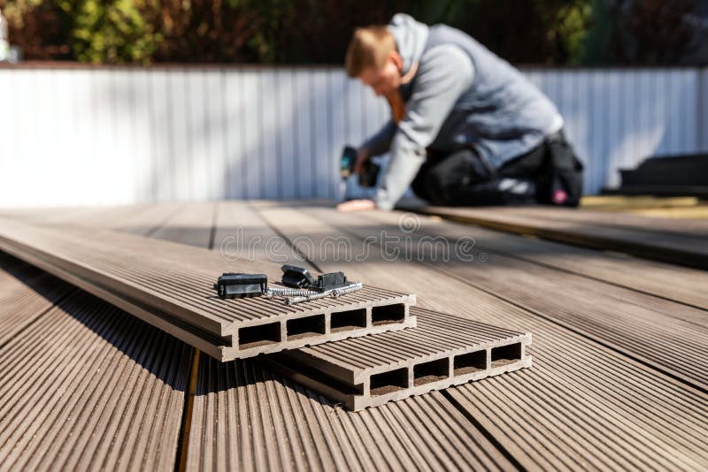 Wpc terrace construction - worker installing wood plastic composite decking boards
