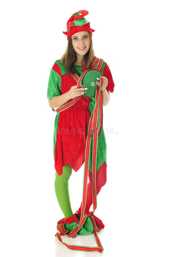 A pretty teen elf looking at the viewer while holding a large spool red and green ribbon. Some of it is wrapped over and around her. On a white background. A pretty teen elf looking at the viewer while holding a large spool red and green ribbon. Some of it is wrapped over and around her. On a white background.