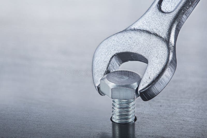 Wrench Tightens Bolt in Steel Billet. Spanner, Bolt, and Nuts Stock