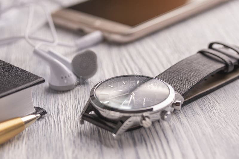 Wristwatch, κινητό τηλέφωνο με τα ακουστικά και ένα σημειωματάριο με μια μάνδρα σε έναν παλαιούς άσπρους υπολογιστή γραφείου και στοκ εικόνα με δικαίωμα ελεύθερης χρήσης Wristwatch, κινητό τηλέφωνο με τα ακουστικά και ένα σημειωματάριο με μια μάνδρα σε έναν παλαιούς άσπρους υπολογιστή γραφείου και στοκ εικόνα με δικαίωμα ελεύθερης χρήσης