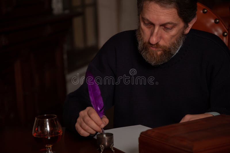 Writer with beard writes on white sheet with quill pen stock images
