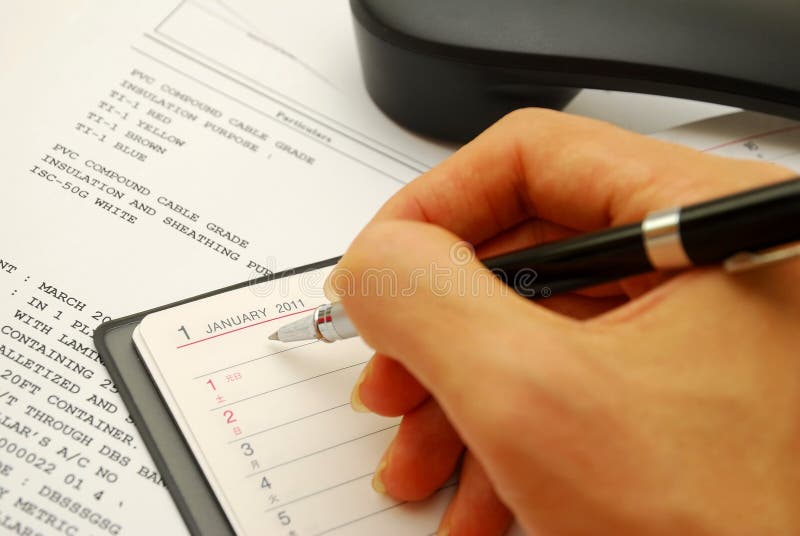 Writing with black pen on planner royalty free stock images