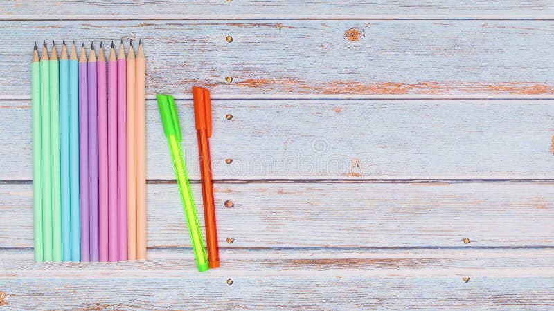 Writing pens, pencils, felt panes and brushes appear on wooden table. Back to school stop motion