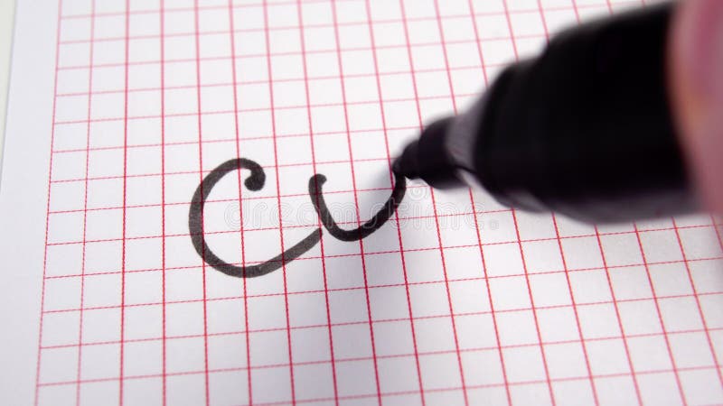 Writing the word COST in a black felt-tip pen on a squared page of a paper notebook