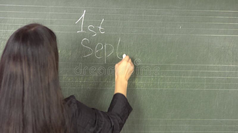 1 września młoda nauczycielka brunetek pisze na tablicy kredą .